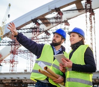 male and female civil engineers in blue head gear on site